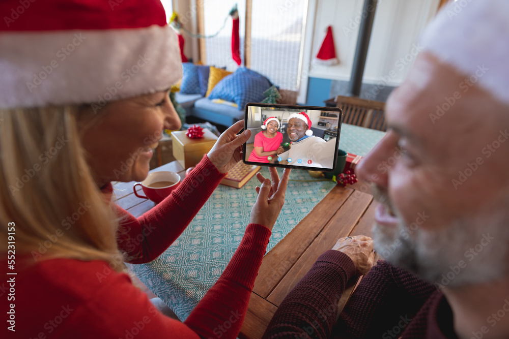 戴着圣诞老人帽的高加索夫妇与一对幸福的非裔美国夫妇进行圣诞视频通话