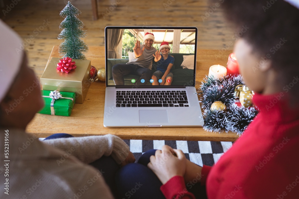 戴着圣诞老人帽的非裔美国夫妇与幸福的高加索家庭进行圣诞视频通话