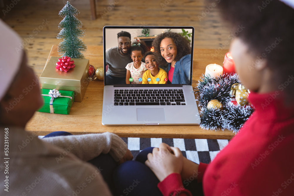 戴着圣诞老人帽的非裔美国人夫妇与非裔美国人家庭进行圣诞视频通话