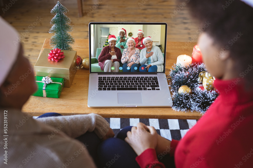 African american couple with santa hats having christmas video call with happy diverse family