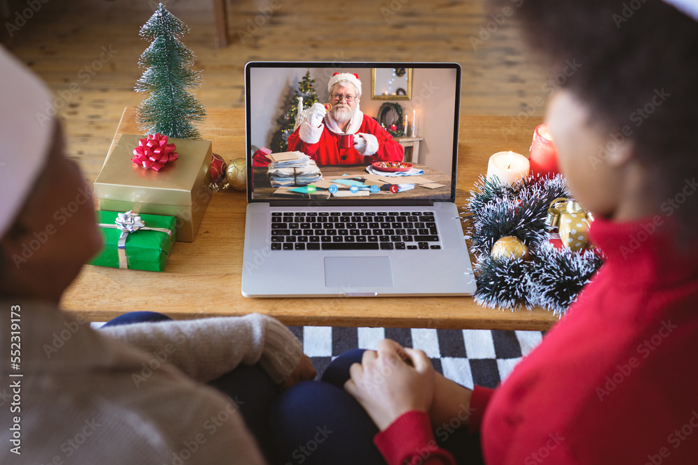 戴着圣诞老人帽的非裔美国夫妇与快乐的高加索圣诞老人进行圣诞视频通话