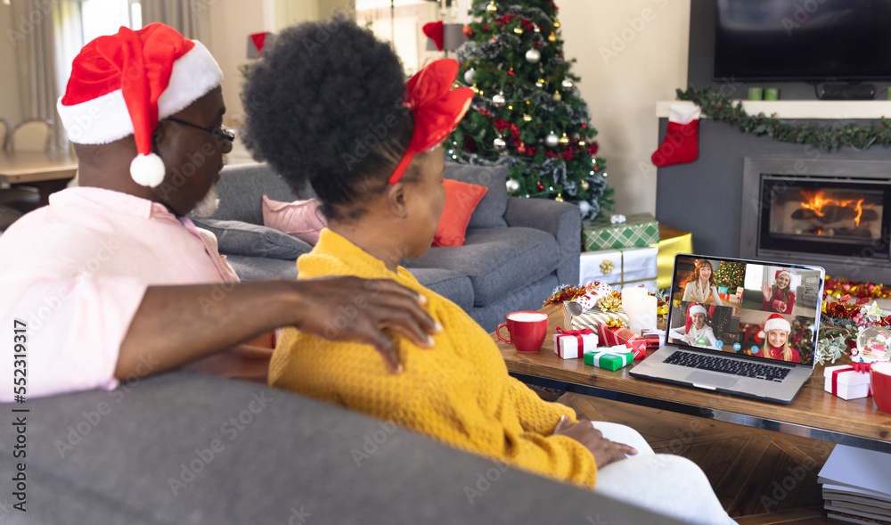 戴着圣诞老人帽的非裔美国夫妇与快乐的高加索朋友视频通话