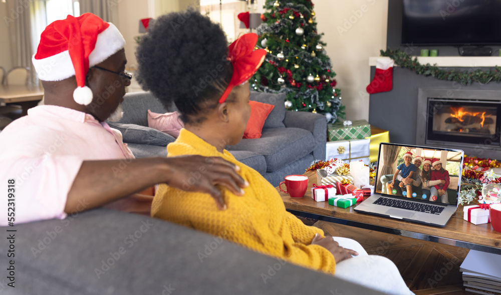 African american couple with santa hat having video call with happy caucasian family