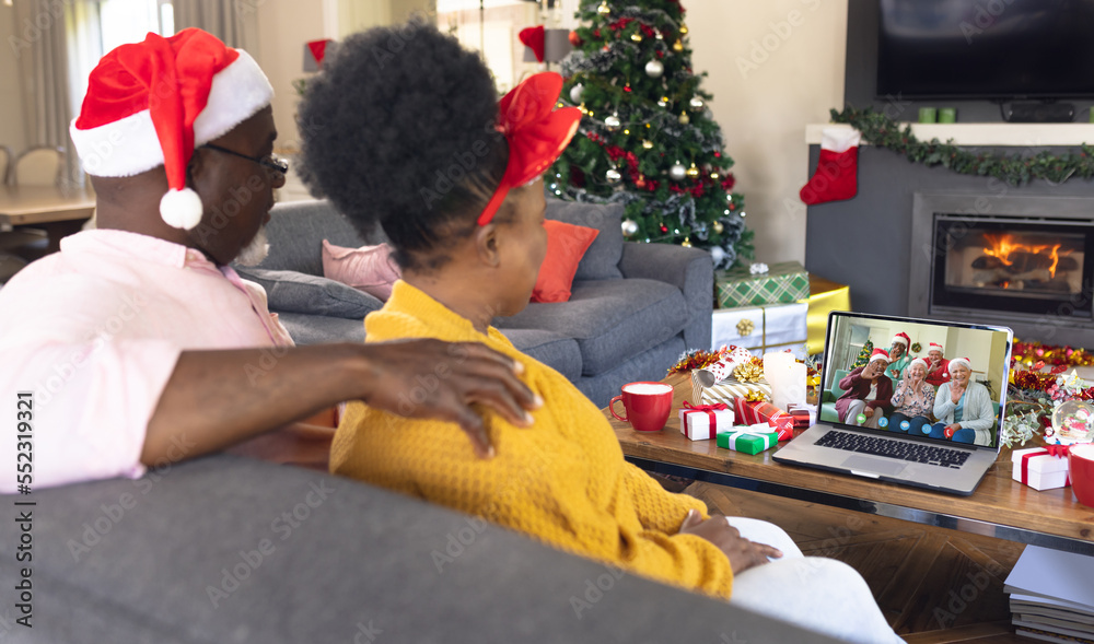 African american couple with santa hat having video call with happy diverse friends