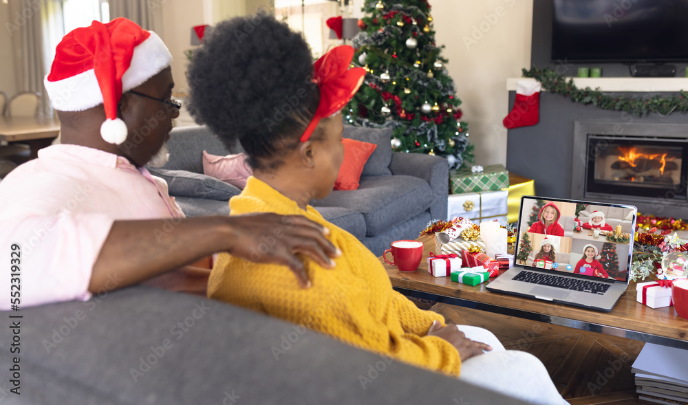 African american couple with santa hat having video call with happy caucasian children