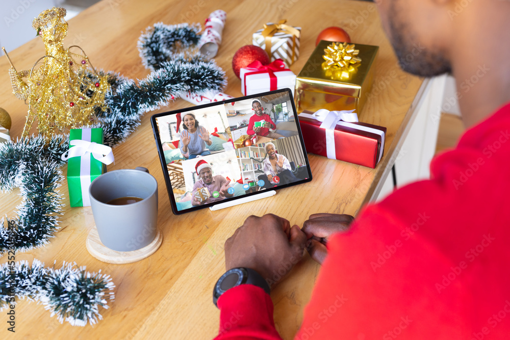 带着圣诞装饰品的非裔美国人与快乐的不同朋友进行视频通话