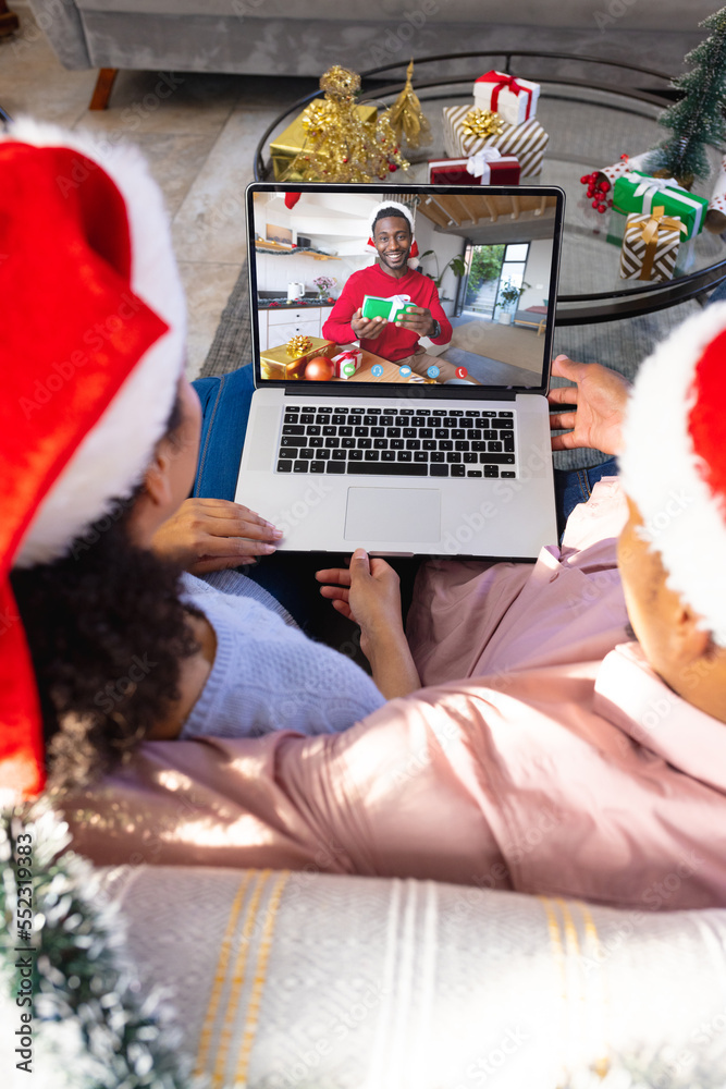 Biracial couple with christmas decorations having video call with happy african american man