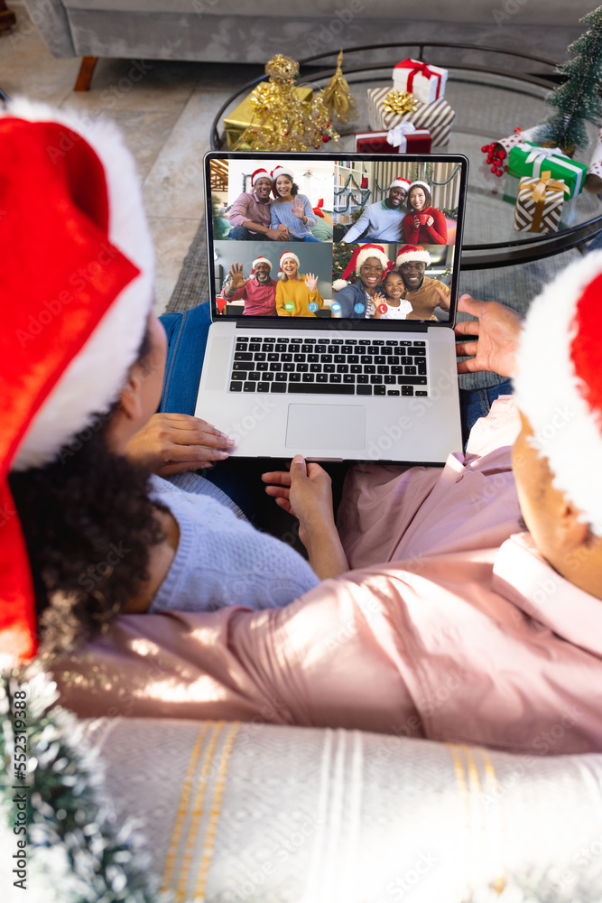 带着圣诞装饰品的混血夫妇与快乐的不同朋友进行视频通话