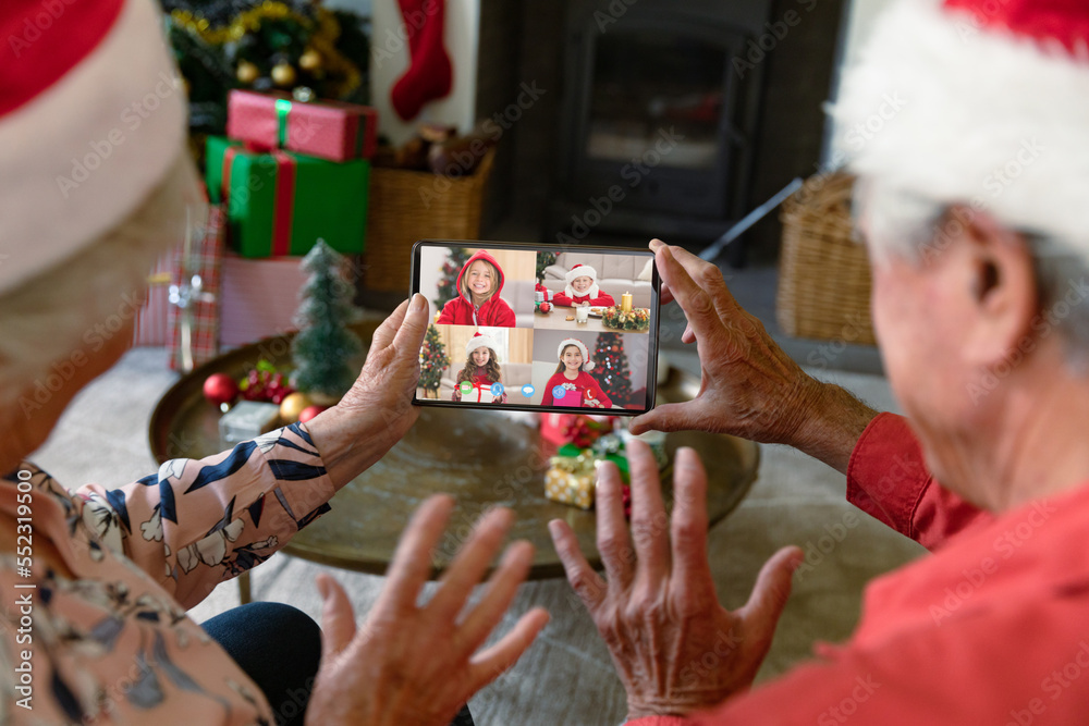 戴着圣诞老人帽的白人老年夫妇与快乐的白人孩子视频通话