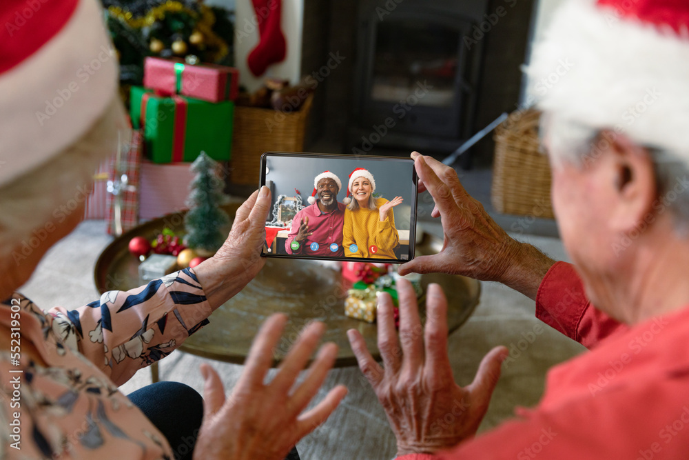 Senior caucasian couple with santa hats having video call with happy diverse couple