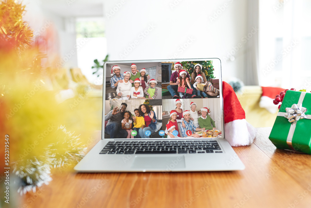 Happy diverse families having christmas laptop video call on table