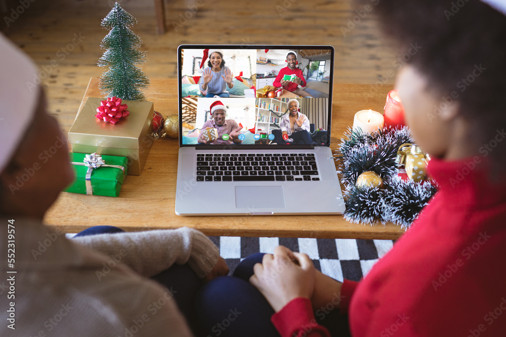 戴着圣诞老人帽的非裔美国人家庭与快乐的不同朋友进行视频通话