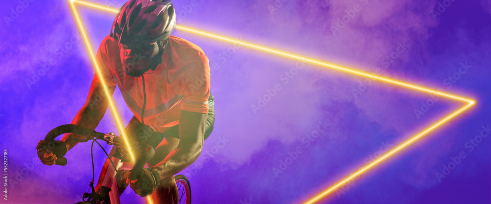非裔美国男性自行车手在烟雾背景下骑着带照明三角形的自行车