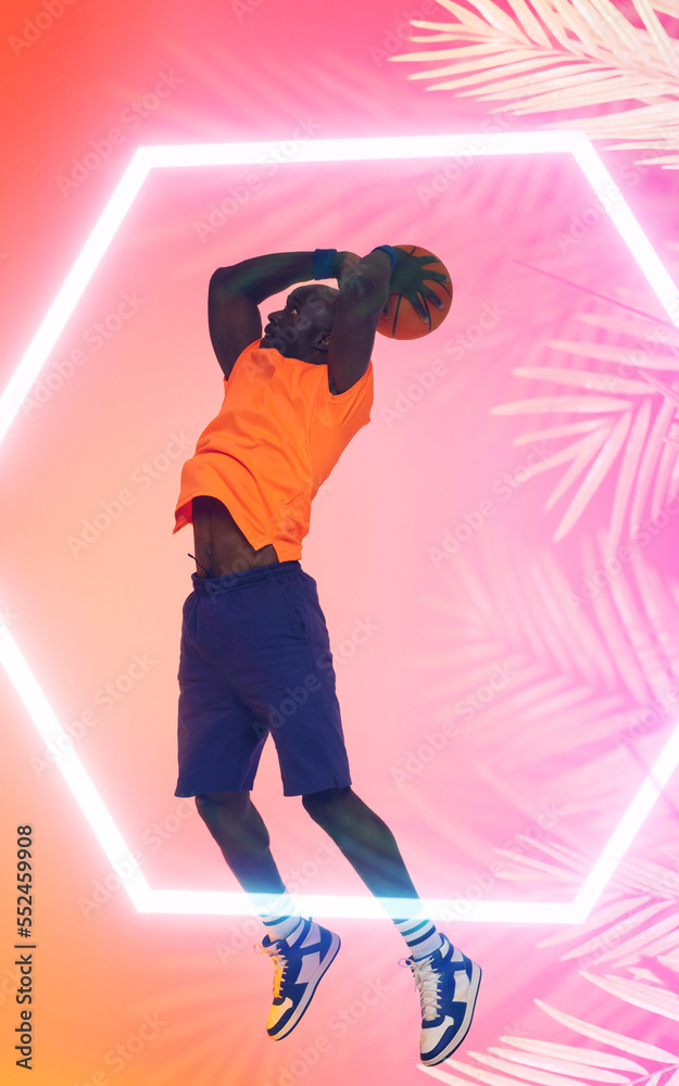 African american male basketball player taking a shot with ball over illuminated hexagon and plants