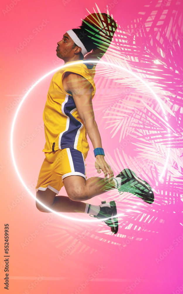 Side view of biracial basketball player jumping and taking a shot with ball by circle and plants