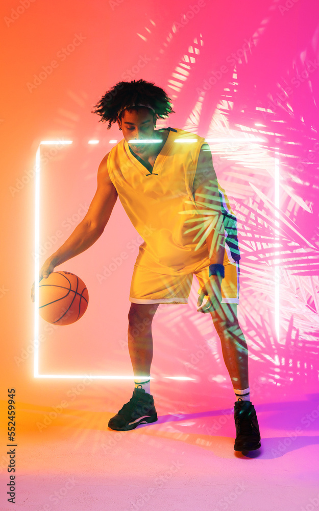 Full length of biracial male player dribbling basketball by illuminated plants and square