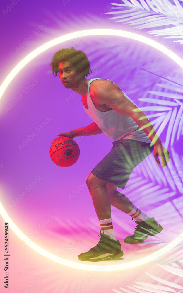 Side view of biracial male player dribbling basketball by illuminated plants and circle, copy space