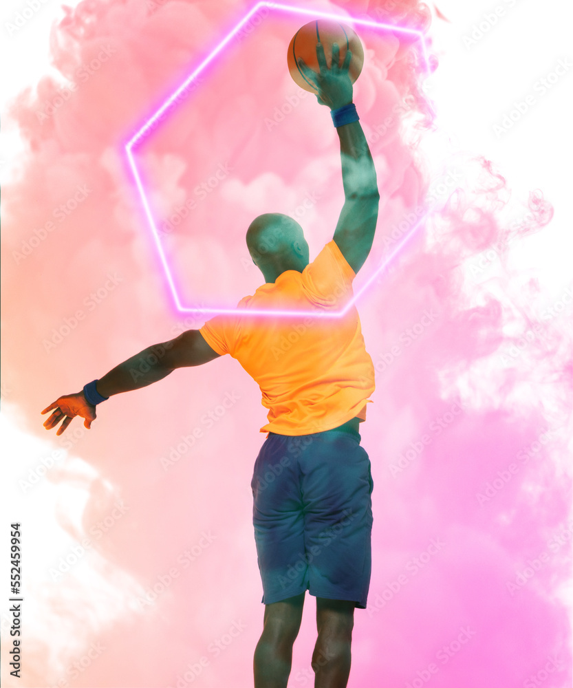 Rear view of african american player taking a shot with basketball by hexagon on smoky background