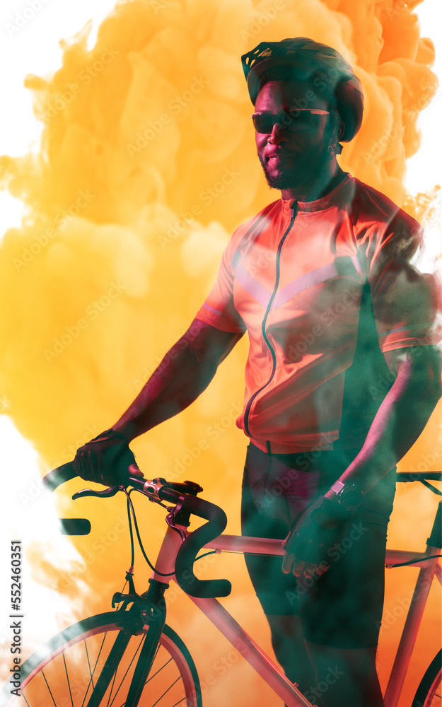 African american male athlete wearing helmet and glasses standing with bike over smoky background