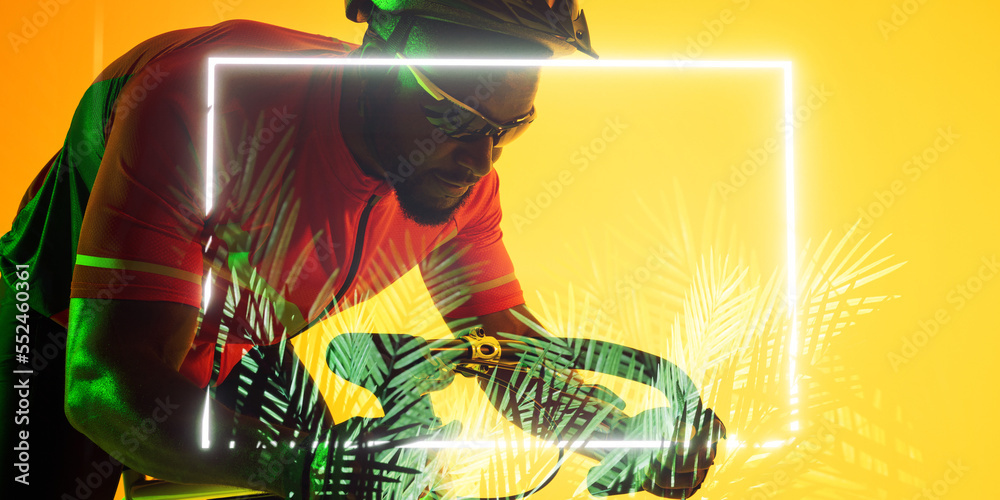 非洲裔美国男性自行车手骑自行车时，用黄色背景的长方形和植物照明