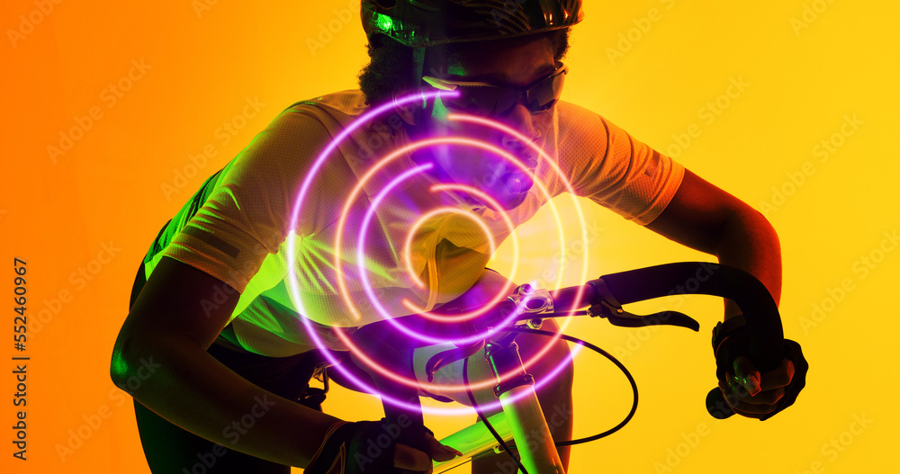 Biracial female cyclist wearing glasses and helmet riding bike over illuminated circular pattern