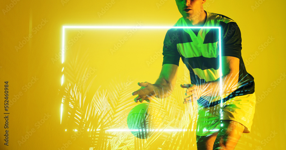 Midsection of caucasian rugby player throwing ball by rectangle and plants over yellow background