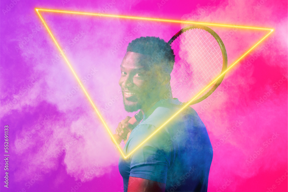 African american male player with racket by glowing triangle amidst smoke on colored background