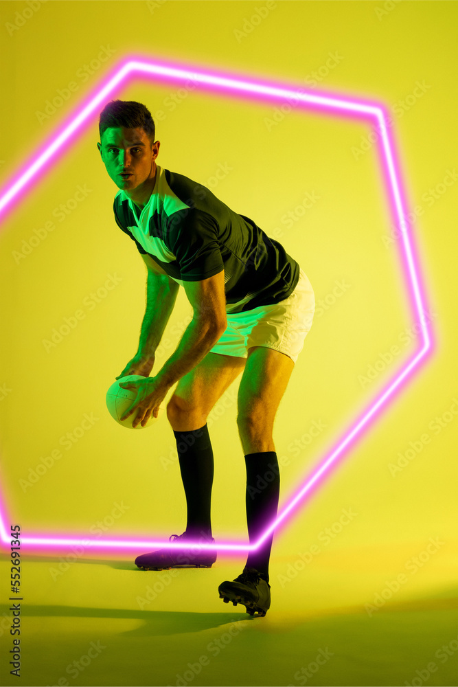 高加索男子橄榄球运动员通过黄色背景上的发光六边形弯下腰投球