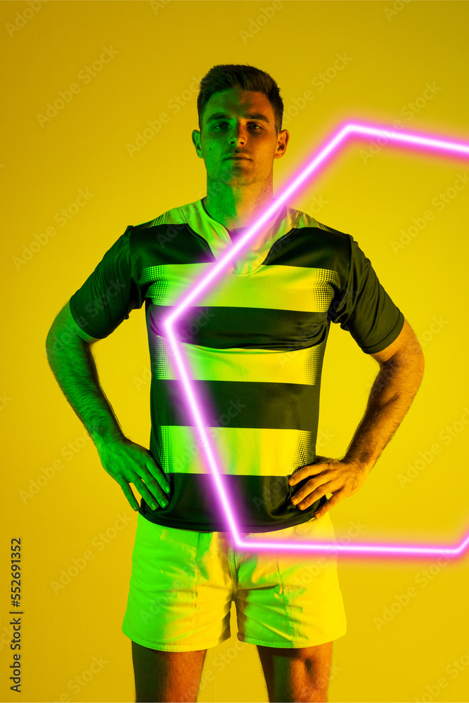 自信的白人男性橄榄球运动员，双手放在臀部，黄色背景上的发光六边形