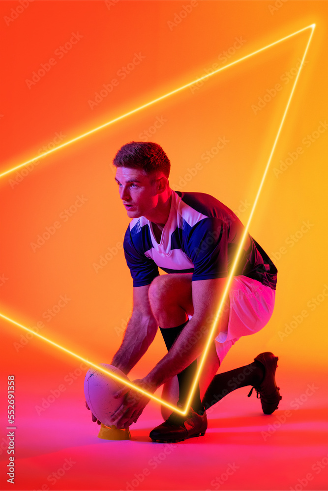 高加索男性球员将橄榄球放在渐变背景上的三角形照明看台上