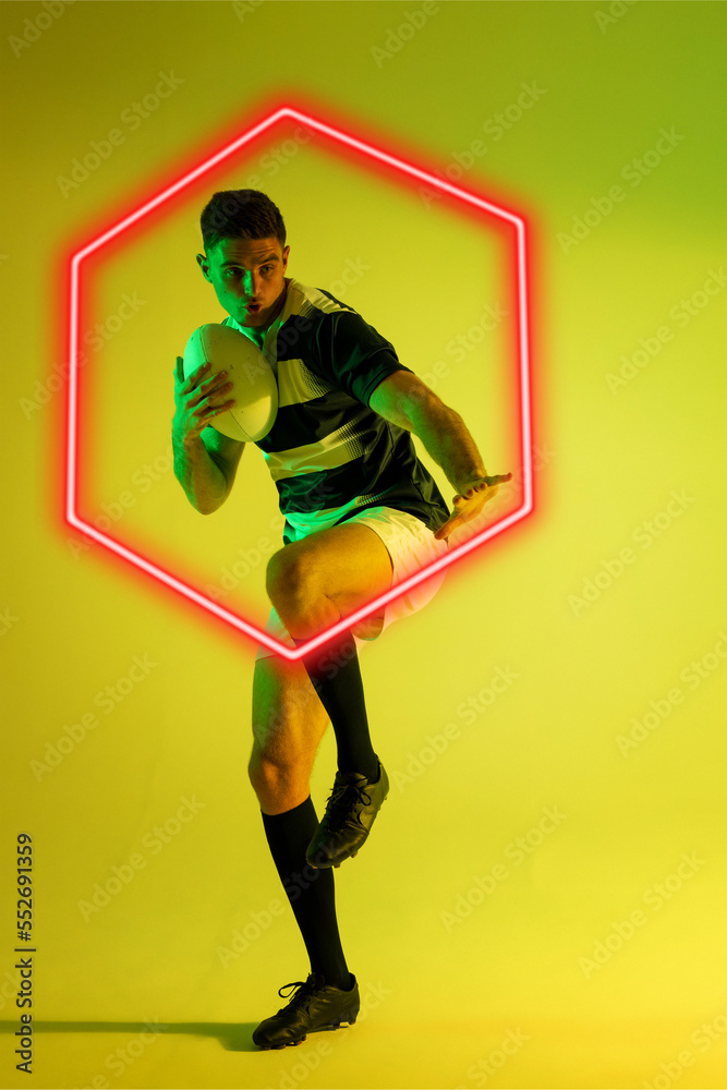 Caucasian male rugby player shooting ball by illuminated hexagon over yellow background