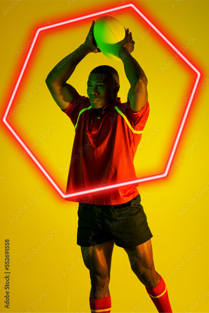 非裔美国男子橄榄球运动员在黄色背景上用发光的六边形投球