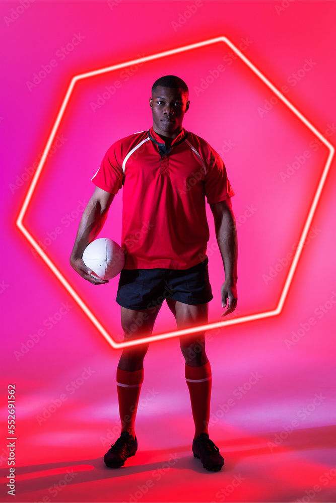 自信的非裔美国男子橄榄球运动员，粉色背景，球在发光的六边形上