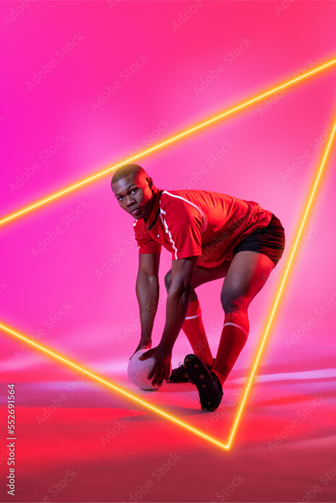 非裔美国男球员，橄榄球被粉红色背景上的发光三角形弯曲