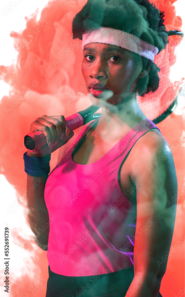 Portrait of african american female tennis player with racket over red smoky background