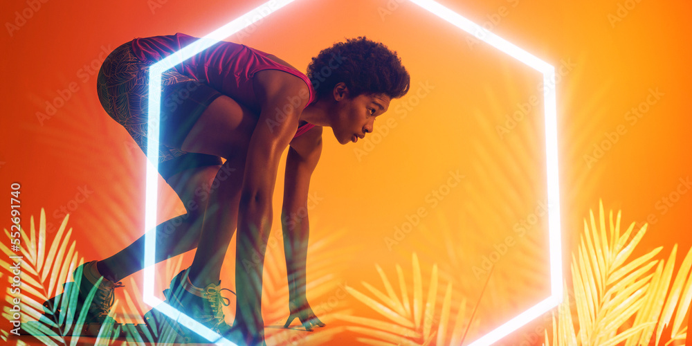 Side view of african american female athlete at starting position by illuminated hexagon and plants