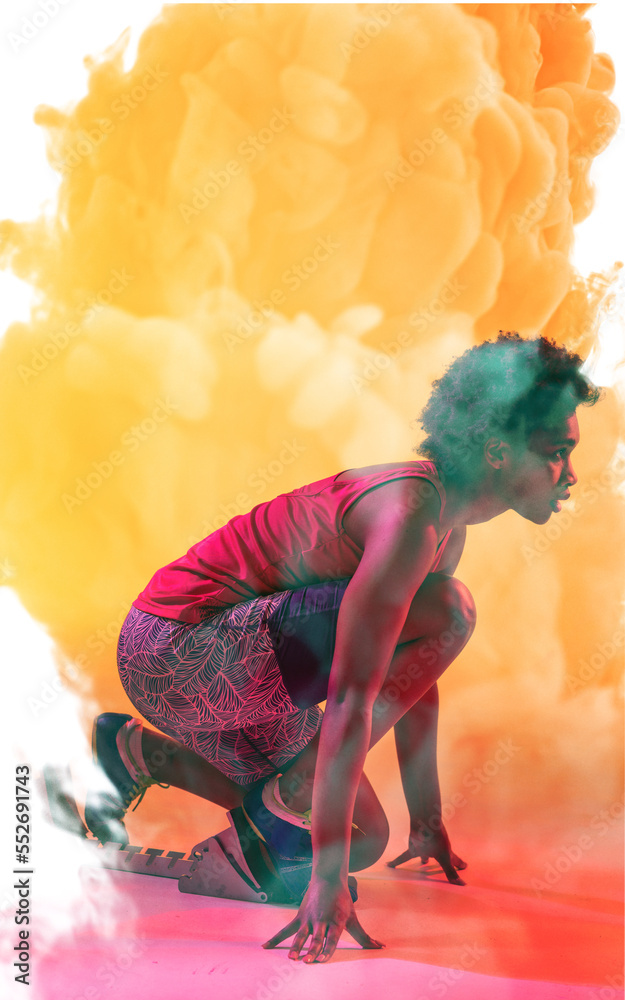 烟雾背景下，非裔美国女运动员蹲在起跑位置的侧视图
