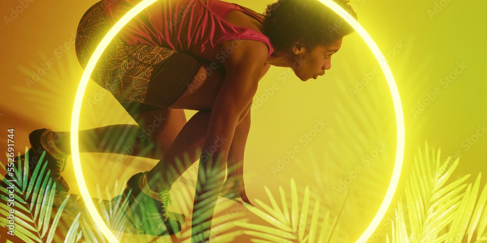 照亮的六边形和植物覆盖着在起跑位置弯腰的非裔美国女运动员