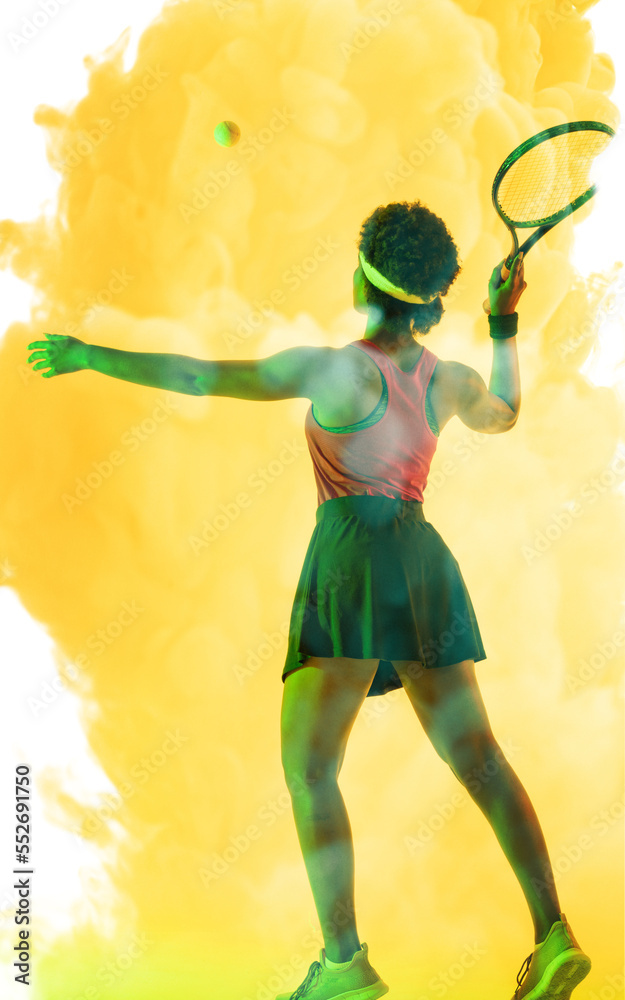 Rear view of african american female player hitting ball with tennis racket on smoky background