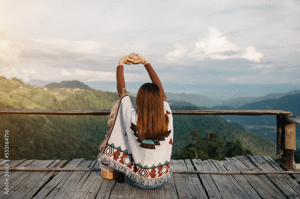  Female traveler sitting and looking at a beautiful mountain,flower field and nature view.