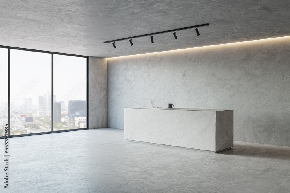 Perspective view on spacious loft style hall concrete reception desk with laptop and tea mug and cit