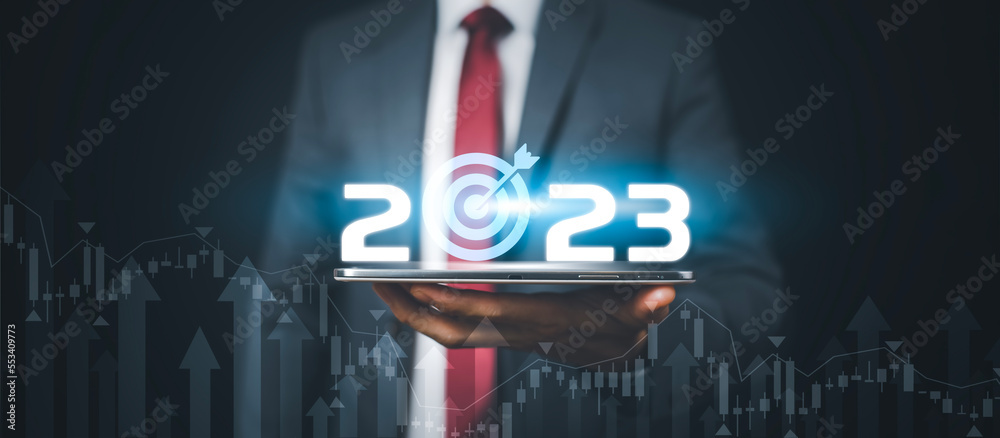 Businessman holds tablets with target and number new year 2023 on the business graph background, Inn
