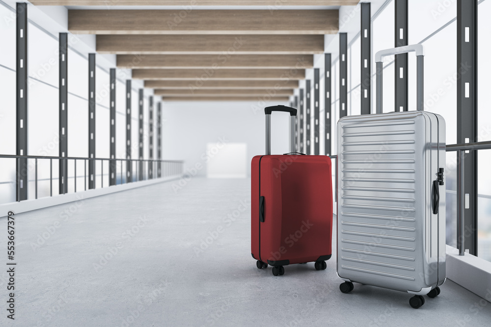 Red and gray suitcases placed in contemporary blurry airport interior with panoramic windows and cit