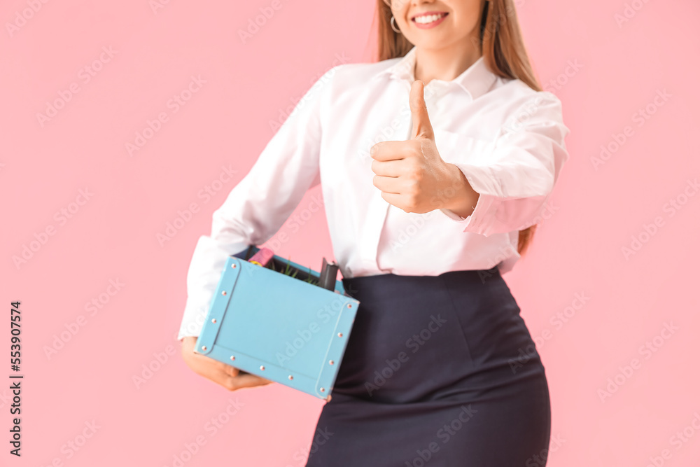 Fired young woman with personal stuff showing thumb-up on pink background, closeup