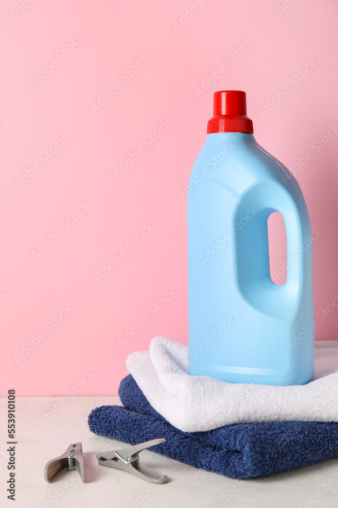 粉红色背景下桌子上的洗衣粉和毛巾