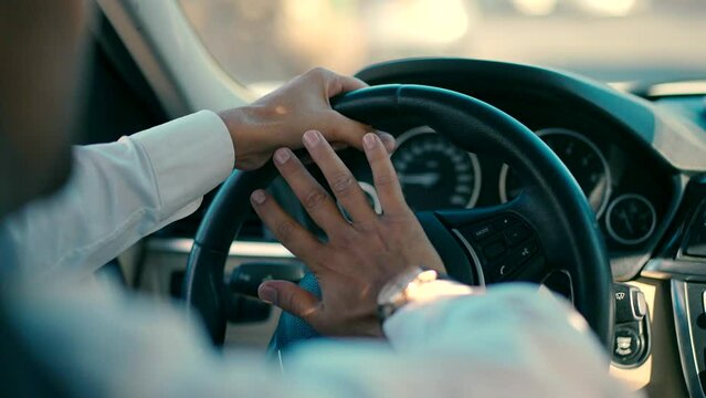 close up male hand honking the car horn during driving a car at day. man in white shirt drives the car and honking the car horn.