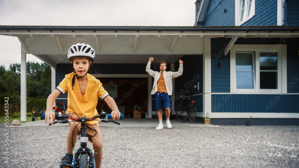快乐父亲带儿子在家前院草坪上骑自行车。小Bo