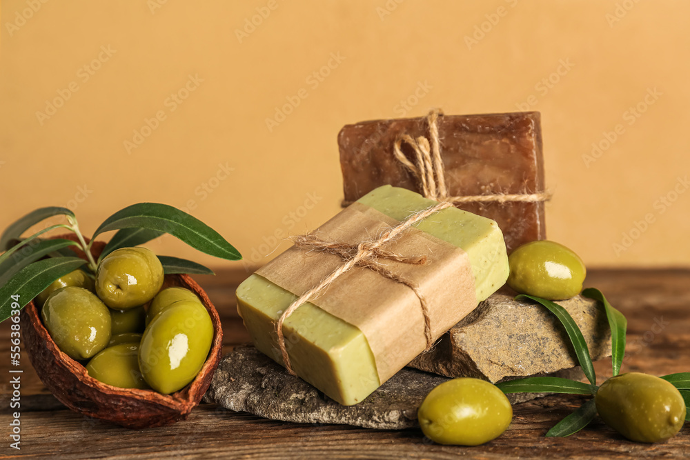 米色墙壁附近的桌子上放着绿橄榄和石头的肥皂条