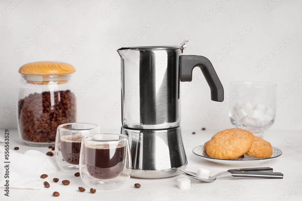 间歇泉咖啡机，一杯意式浓缩咖啡，装着豆子和饼干的罐子，盘子里有白色背景