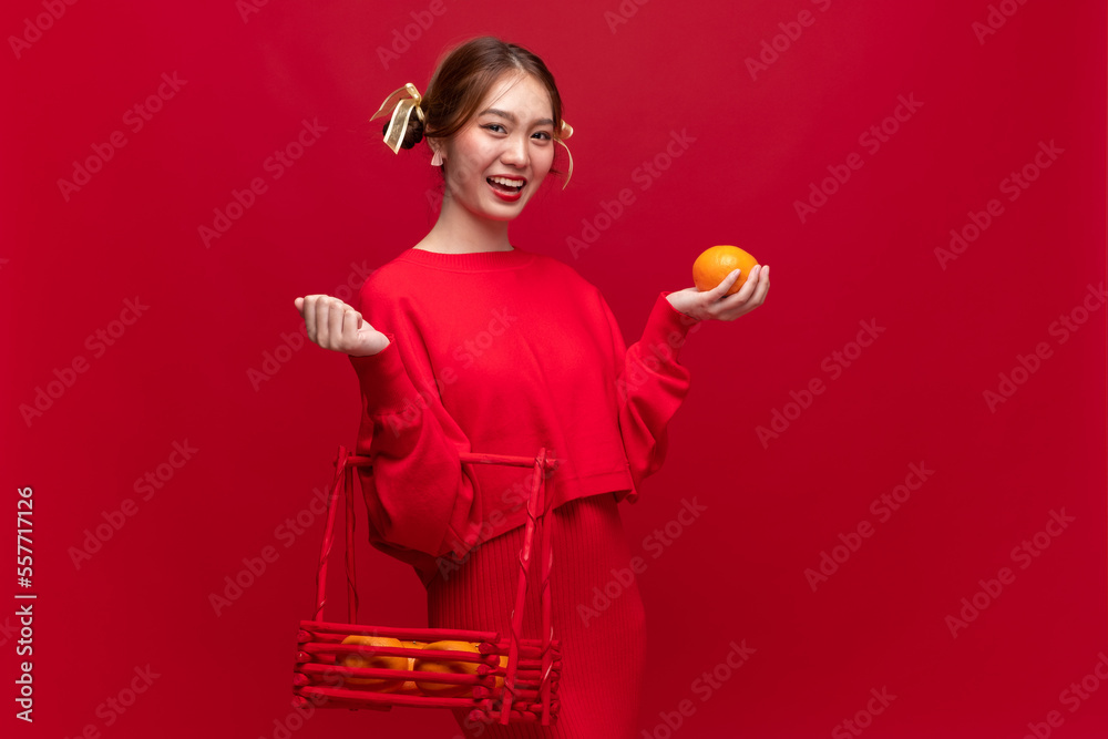 年轻的亚洲女性穿着红色毛衣连衣裙，红色背景为橙色，代表中国新年